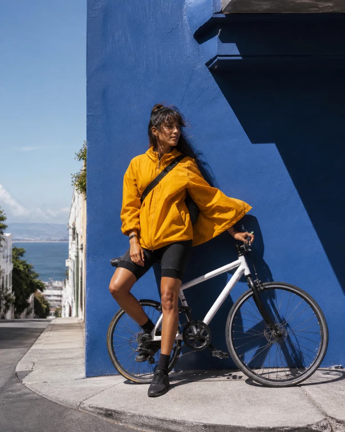 Source reference: A fictional adult bicycle messenger in a saffron jacket beside a cobalt wall